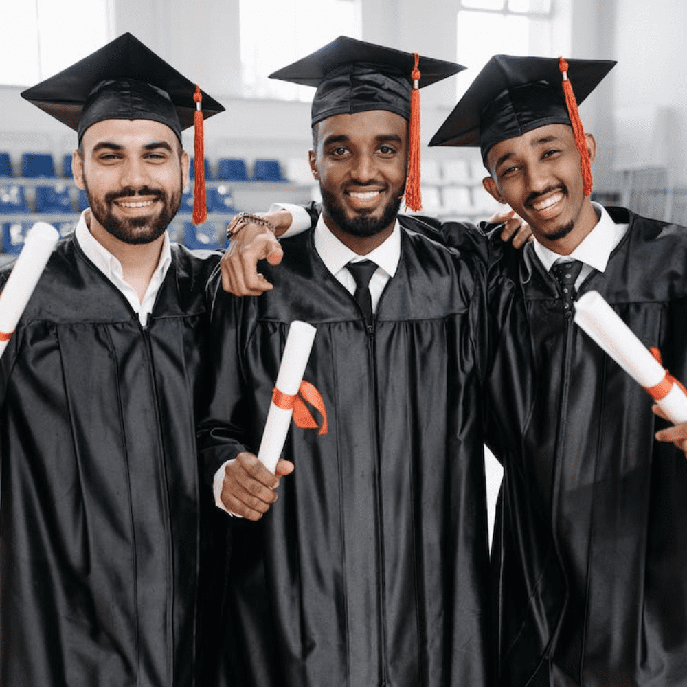 Three men in graduation gowns holding their diplomas.