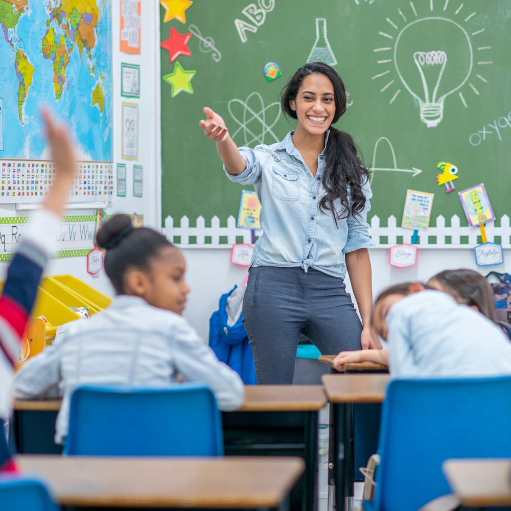 A teacher is pointing to the sky in front of her students.