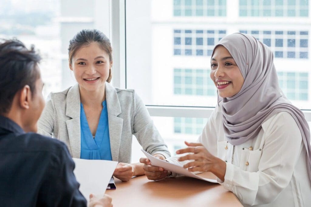 Two women sitting at a table with papers in front of them.