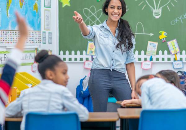 A teacher is pointing to the sky in front of her students.