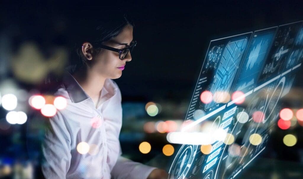 A woman interacts intently with futuristic holographic screens at night, the city lights blurred in the background.