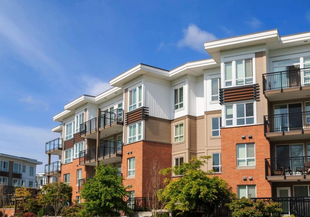 Modern residential building with balconies, hosting an online education center, featuring a mix of brick and white paneling under a clear blue sky.