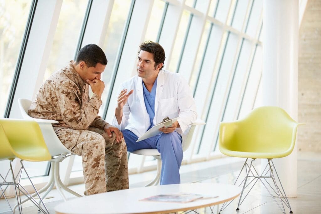 A doctor in a white coat consults with a soldier in camouflage uniform about online education in a modern, bright waiting room with large windows.