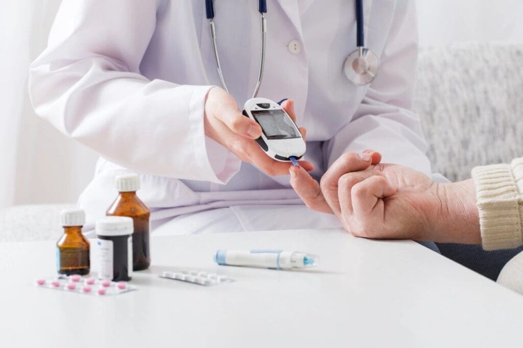 Doctor measuring a patient's blood sugar level using a glucometer, with online education materials visible on the table.