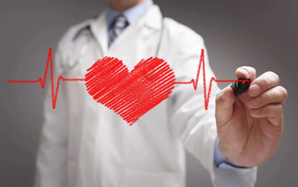 A doctor in a white coat drawing a red heart connected to an ekg line on a transparent surface during an online education session.