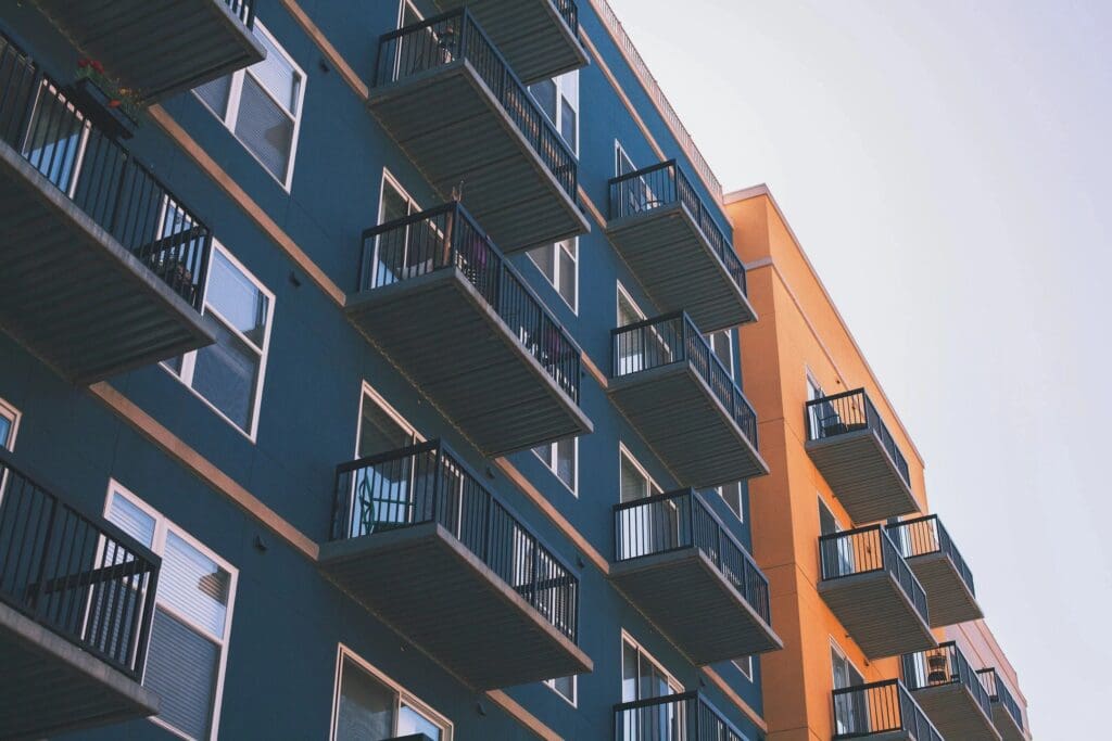 Low angle view of a modern apartment building with blue and orange facades and multiple balconies, advertising online education.