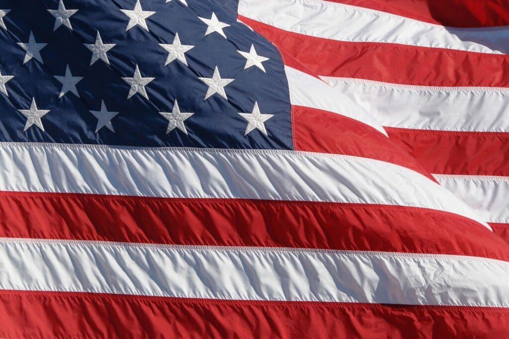 Close-up of the american flag, showing detailed texture of the fabric, with a focus on the stars and stripes in red, white, and blue.