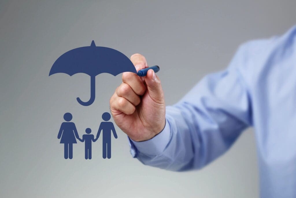 A person's hand drawing a blue umbrella over a family icon, symbolizing protection or insurance.