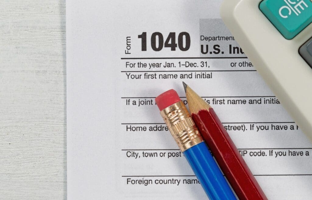 U.s. income tax form 1040 with a pencil and calculator on a desk, emphasizing the section for personal information.