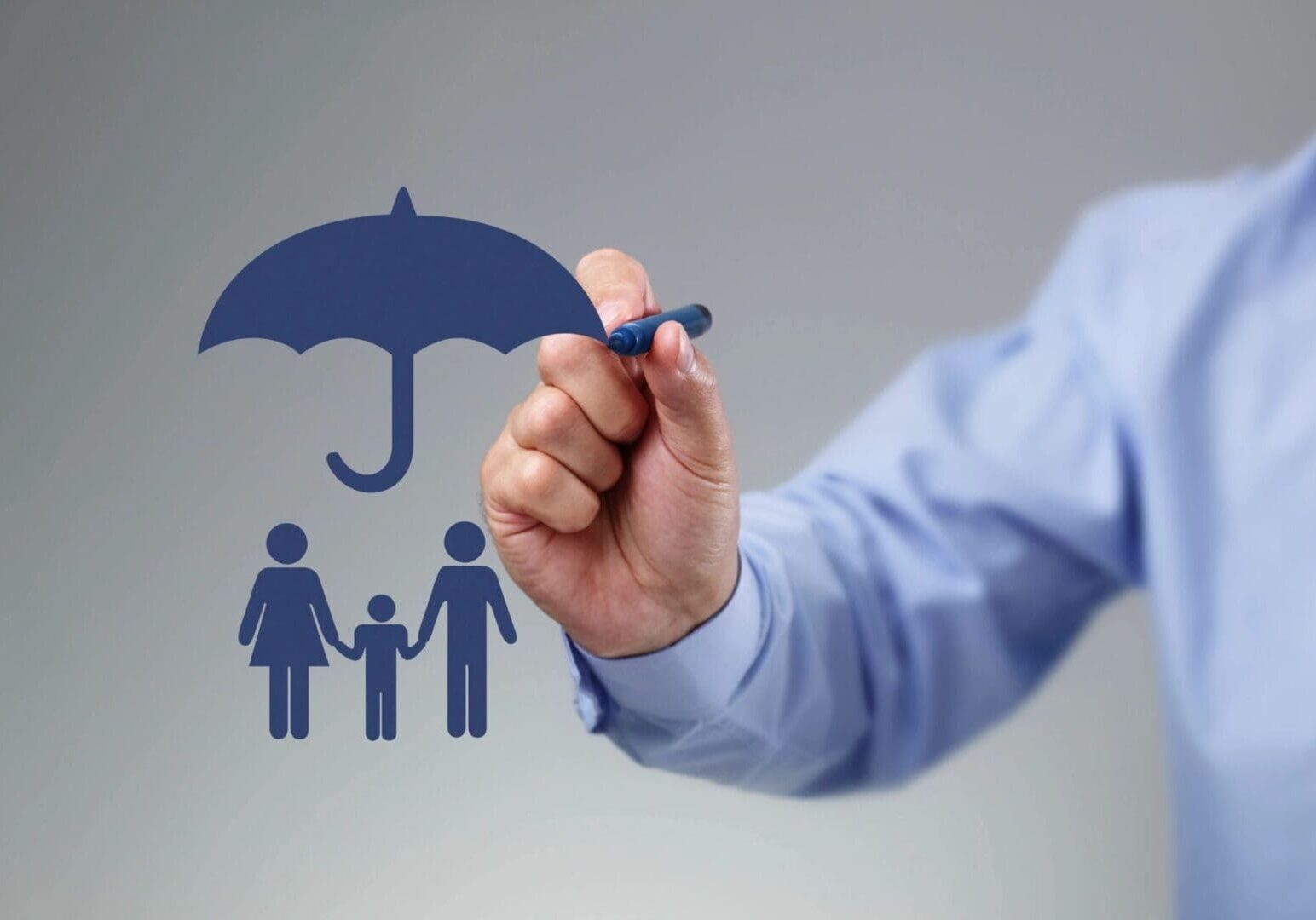 A person's hand drawing a blue umbrella over a family icon, symbolizing protection or insurance.