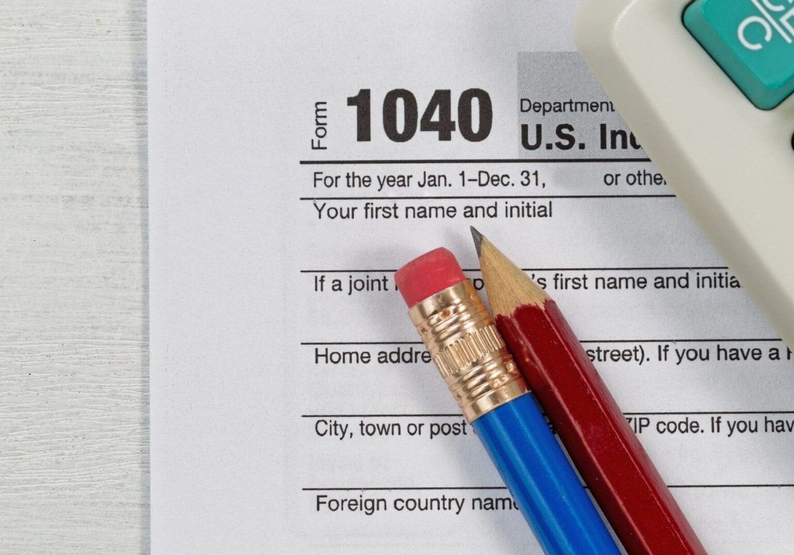 U.s. income tax form 1040 with a pencil and calculator on a desk, emphasizing the section for personal information.